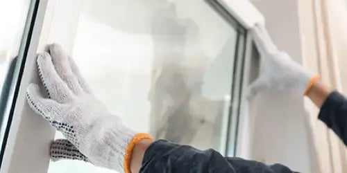 Technician replacing broken window glass in a home